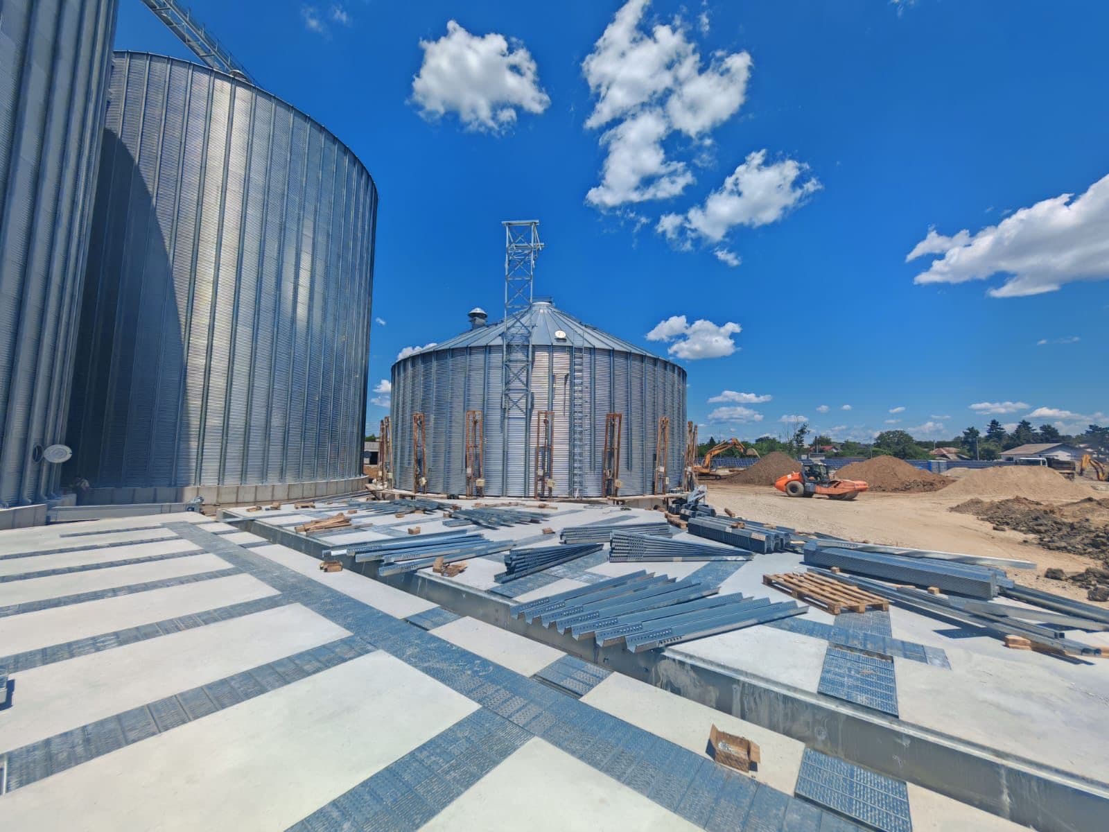 Engineering blueprints on a light table with a grain storage facility visible through the window