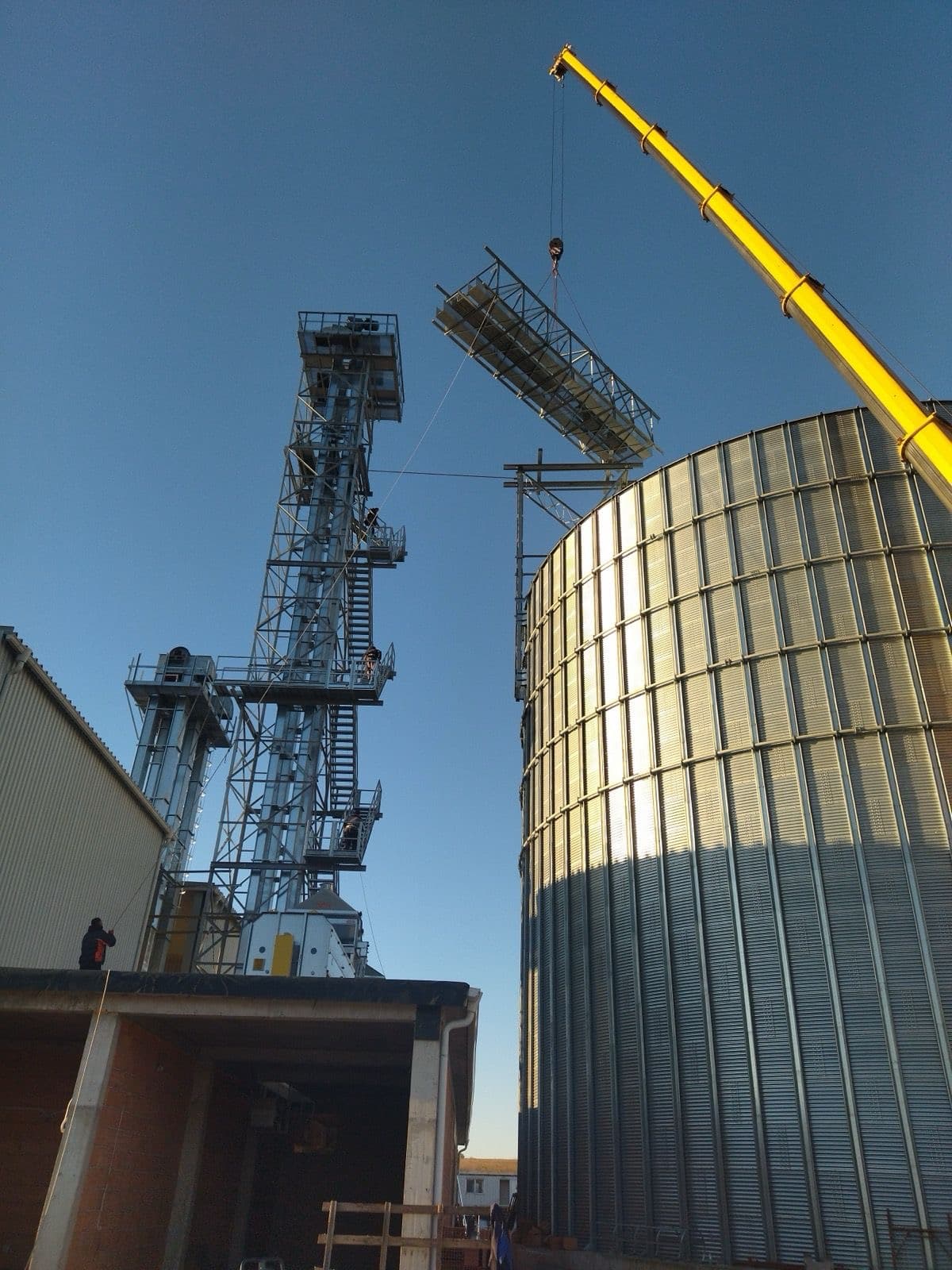 Grain silo complex with industrial conveyors at golden hour